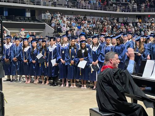 graduates standing at attention in Bob Jones cap and gown